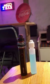 En vape (e-sigarett) og en flaske vapejuice avbildet i en bar