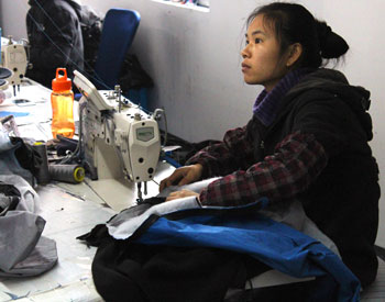 Bilde av en kvinnelig tekstilarbeider som syr.